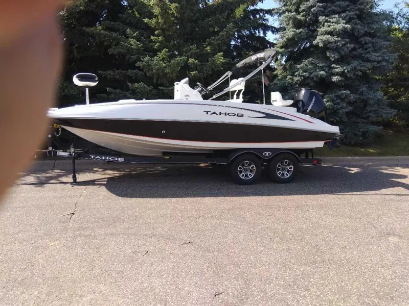 Slide: The Image of 2023 Tahoe 2150 CC boat on trailer, parked outdoors with trees in the background. - 4