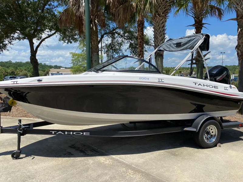 Slide: The Image of 2023 Tahoe 200 S boat on trailer, parked outdoors under palm trees. - 0