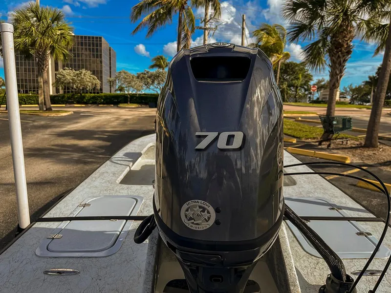 Slide: The Image of 2022 Bossman 17 Flats Boat with 70 HP engine, parked under palm trees. - 4