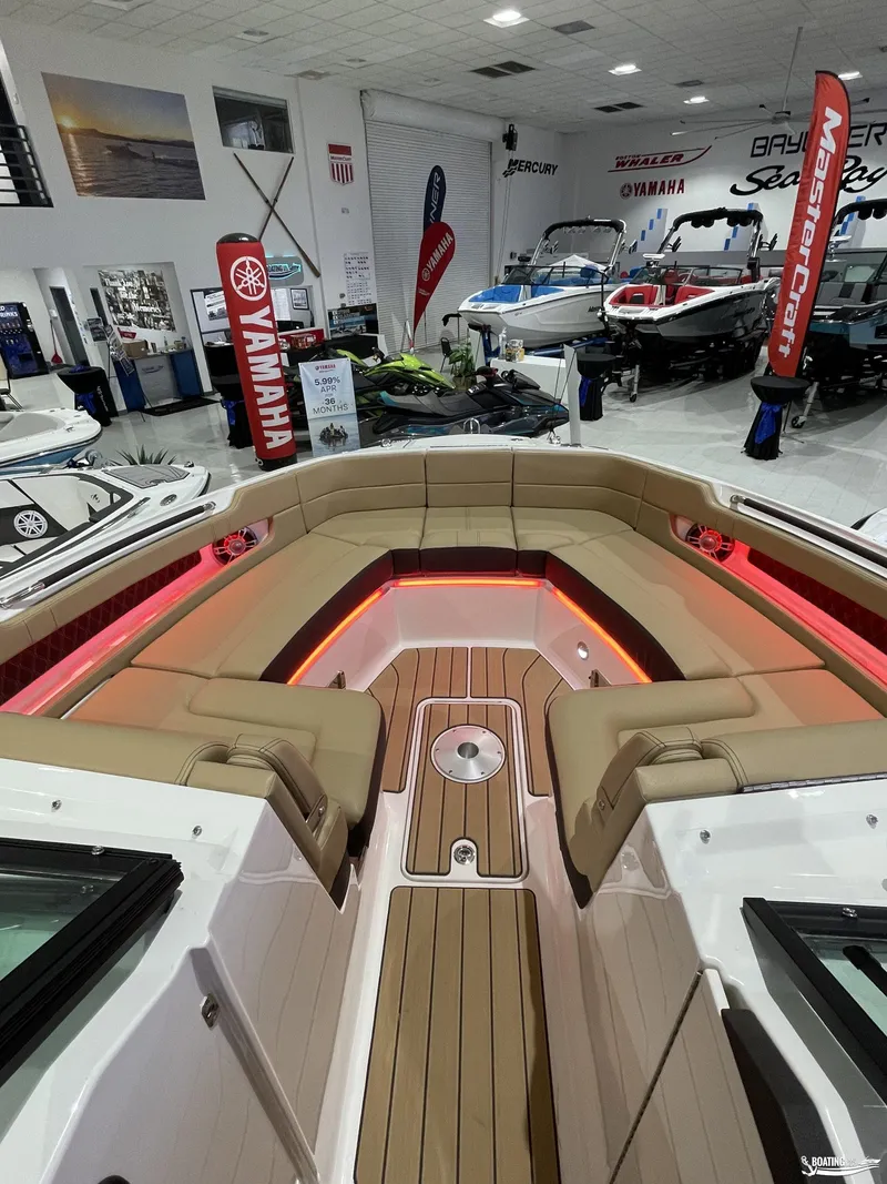 Slide: The Image of 2023 Sea Ray 310 SLX boat interior with tan seating and ambient lighting in showroom. - 20