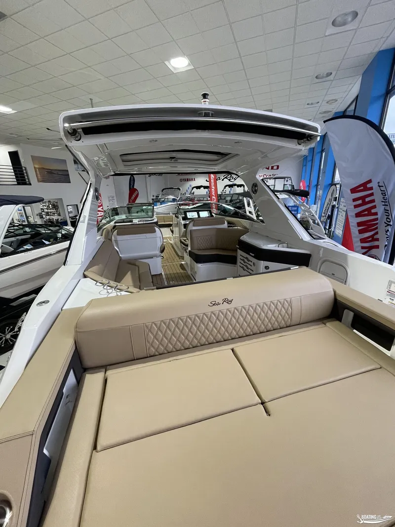 Slide: The Image of 2023 Sea Ray 310 SLX luxury boat interior with beige seating in showroom. - 3