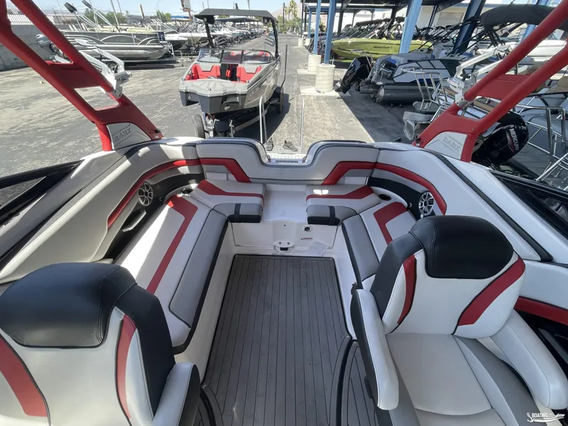 Slide: The Image of 2018 Yamaha Boats 242 X E Series interior with red and white seating, docked among other boats. - 10