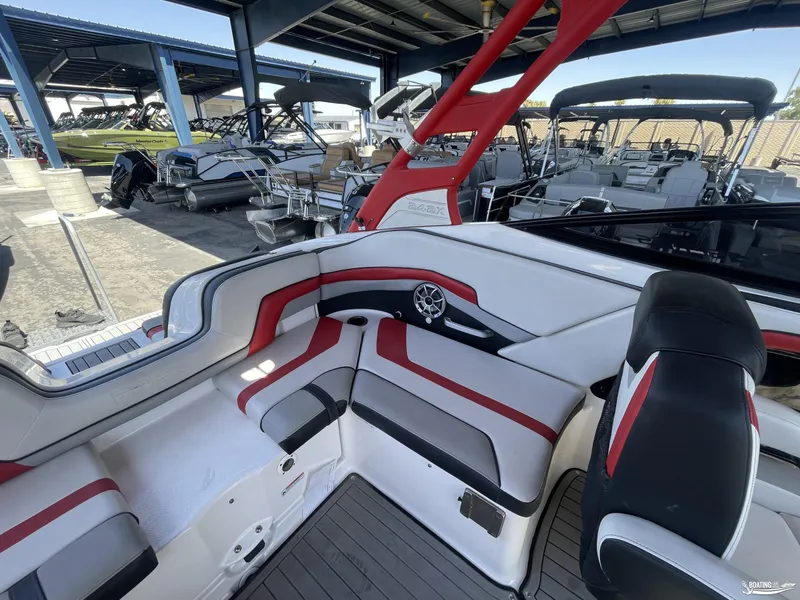 Slide: The Image of 2018 Yamaha Boats 242 X E Series interior with red and white seating, docked in a marina. - 6