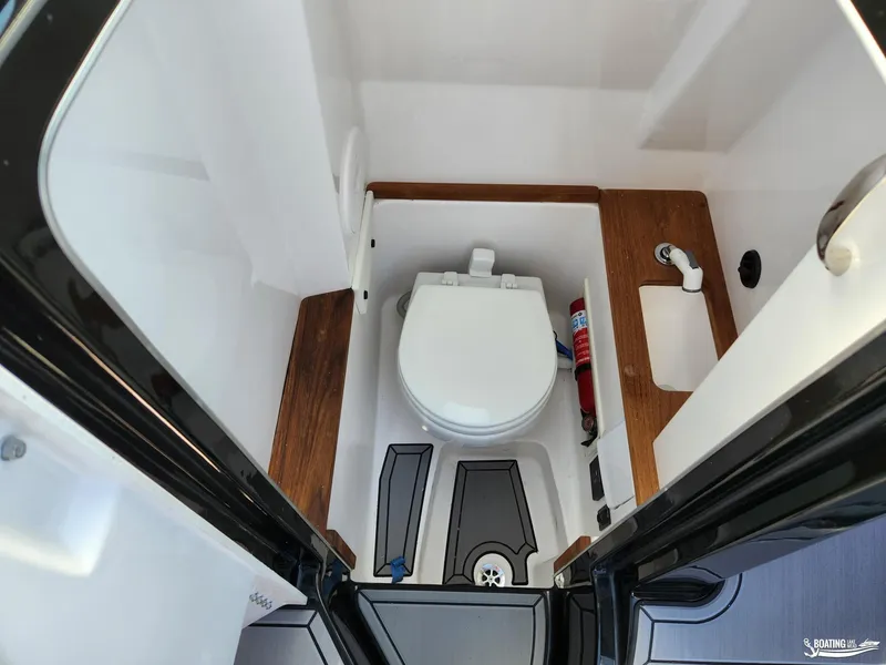 Slide: The Image of 2023 MasterCraft X26 boat bathroom with toilet, sink, and wooden accents. - 9