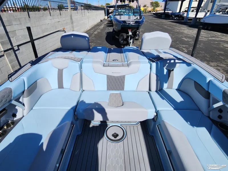 Slide: The Image of 2023 MasterCraft XT23 boat interior with blue and gray seating, docked outdoors. - 15