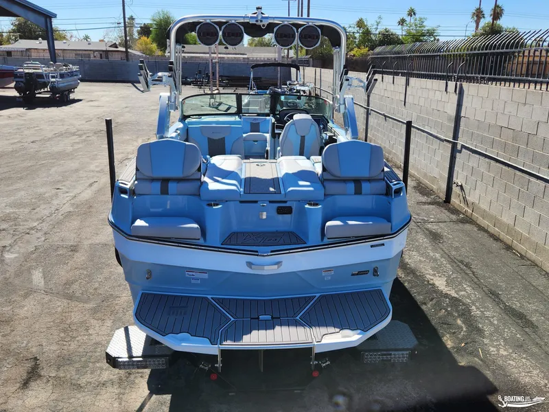 Slide: The Image of 2023 MasterCraft XT23 boat with blue and white seating, parked outdoors. - 5