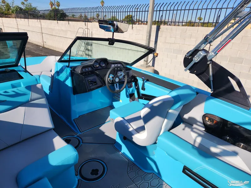 Slide: The Image of 2023 MasterCraft NXT20 boat interior with blue and white seating, steering wheel, and dashboard. - 12
