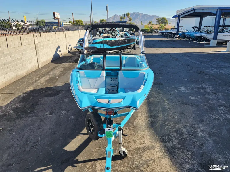 Slide: The Image of 2023 MasterCraft NXT20 boat in bright blue, parked outdoors on a sunny day. - 18