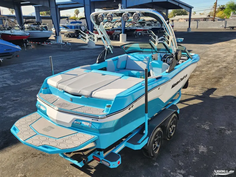 Slide: The Image of 2023 MasterCraft NXT20 boat in vibrant blue, parked on a trailer in a marina. - 19