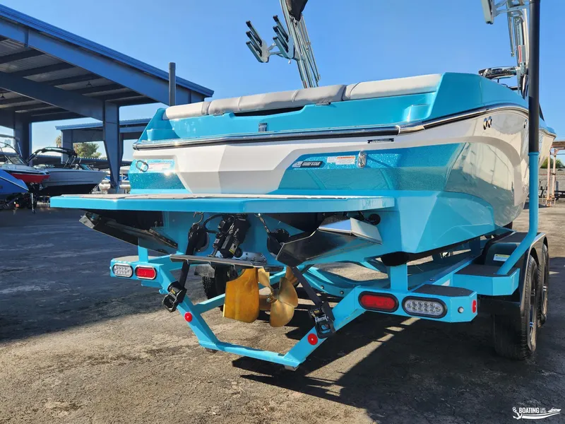 Slide: The Image of 2023 MasterCraft NXT20 boat, blue and white, on a trailer in a marina. - 21