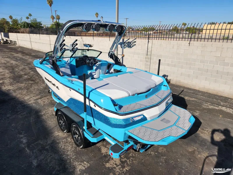 Slide: The Image of 2023 MasterCraft NXT20 boat in vibrant blue and white, parked on a trailer. - 24