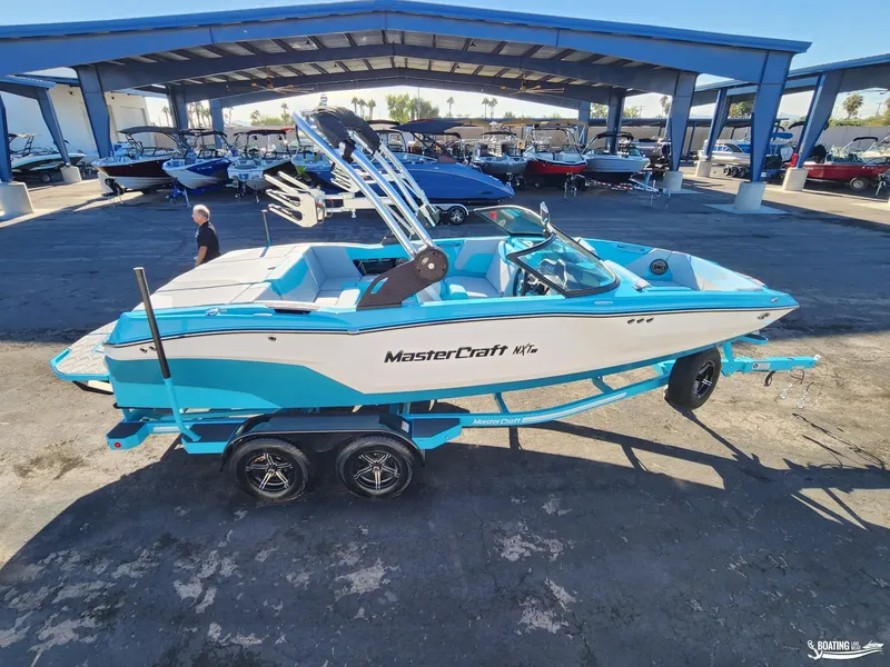 Slide: The Image of 2023 MasterCraft NXT20 boat in blue and white on a trailer at a dealership. - 3