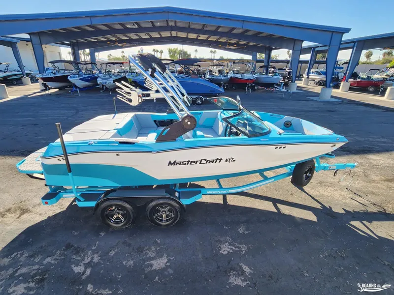 Slide: The Image of 2023 MasterCraft NXT20 boat in blue and white, parked at a dealership. - 4