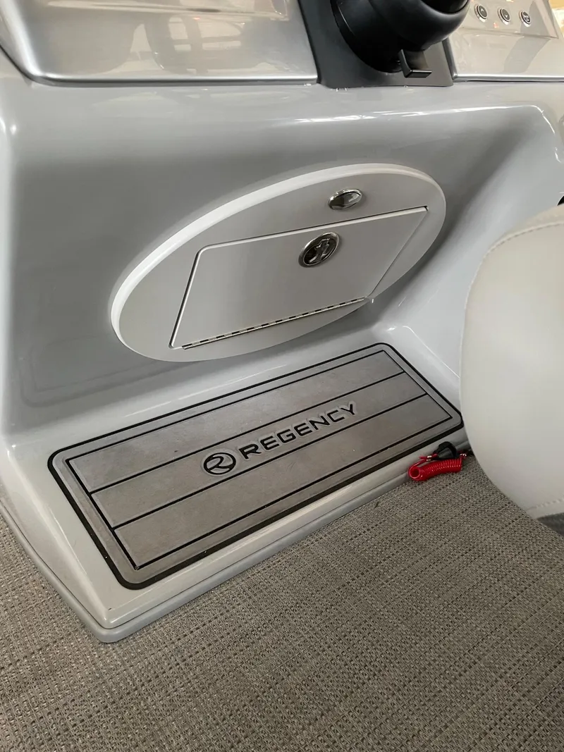 Slide: The Image of 2023 Regency 230 LE3 boat dashboard with storage compartment and branded mat. - 5