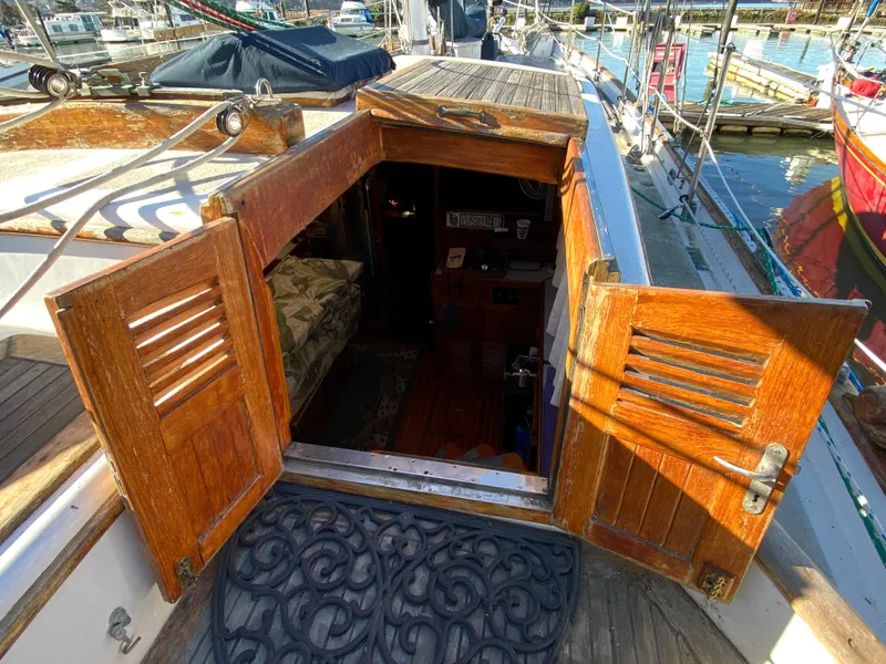 Slide: The Image of Wooden cabin entrance on a 1979 CT 48 sailboat, docked at a marina. - 16