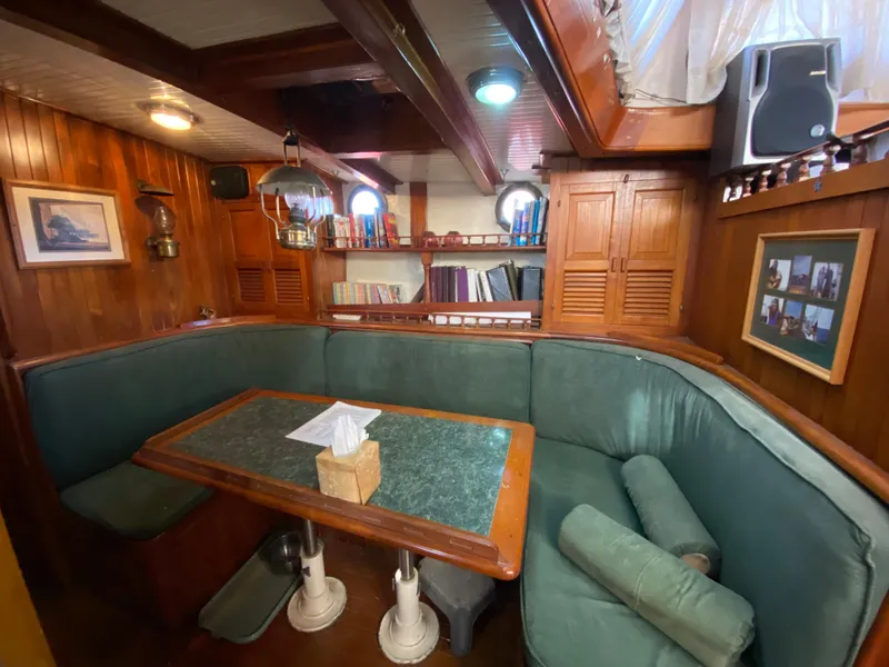 Slide: The Image of Cozy wooden boat interior with green cushioned seating, table, and nautical decor, CT 48, 1979. - 22