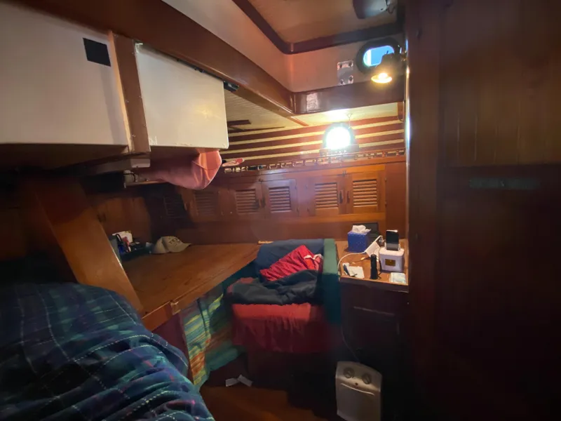 Slide: The Image of Cozy cabin interior of 1979 CT 48 sailboat with wooden furnishings and bedding. - 34