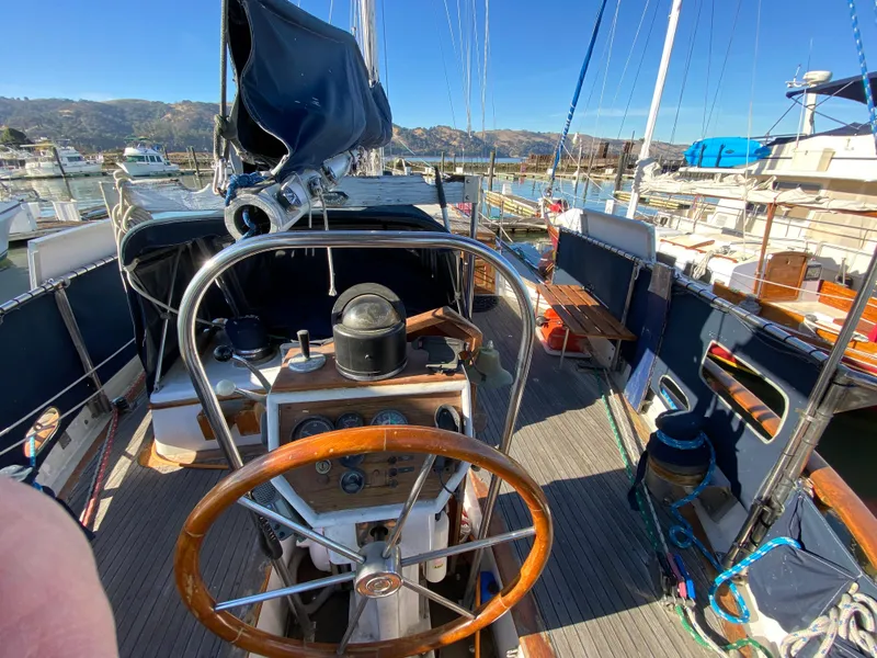Slide: The Image of 1979 CT 48 sailboat cockpit with wooden steering wheel, docked in a marina. - 8