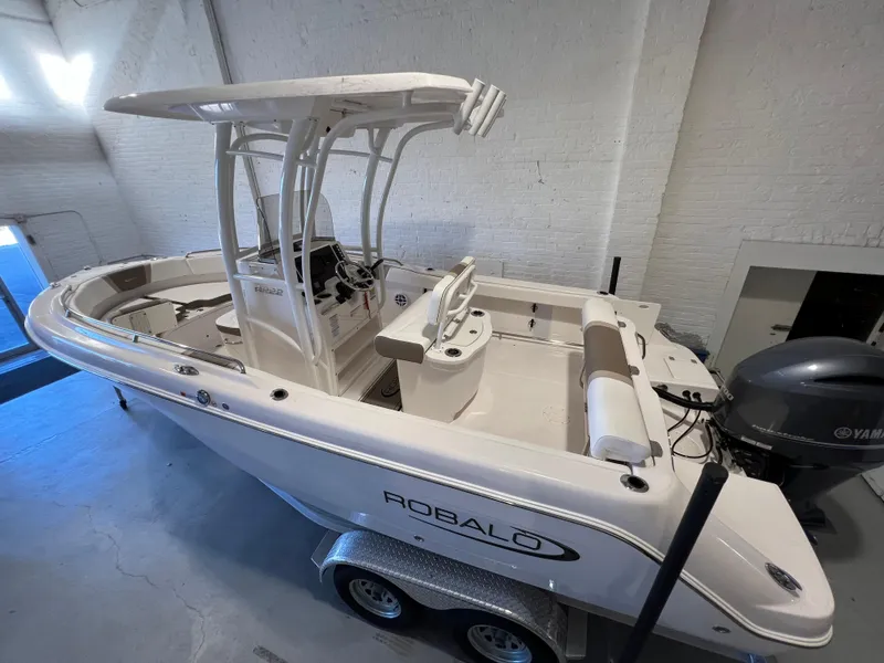 Slide: The Image of 2023 Robalo R222 Center Console boat in a showroom, featuring a sleek design and Yamaha engine. - 2