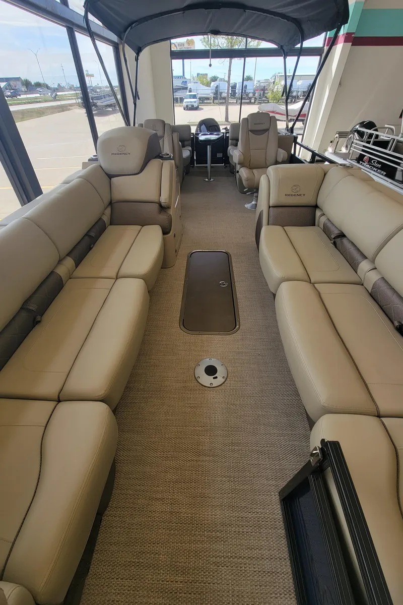 Slide: The Image of 2023 Regency 250 LE3 pontoon boat interior with beige seating and canopy. - 3