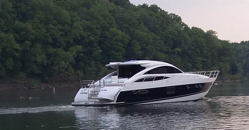 Slide: The Image of 2006 Princess V70 yacht cruising on a serene lake with lush green forest backdrop. - 17