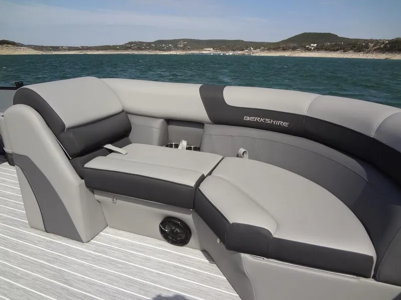 Slide: The Image of 2023 Berkshire 24UL CTS 3.0 boat interior with gray seating, on a scenic water backdrop. - 12