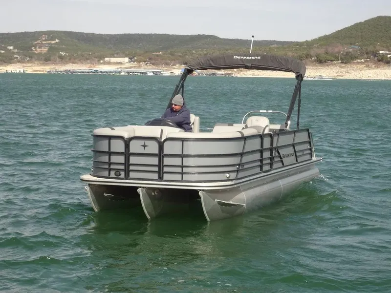 Slide: The Image of 2023 Berkshire 24UL CTS 3.0 pontoon boat on a lake with scenic background. - 3