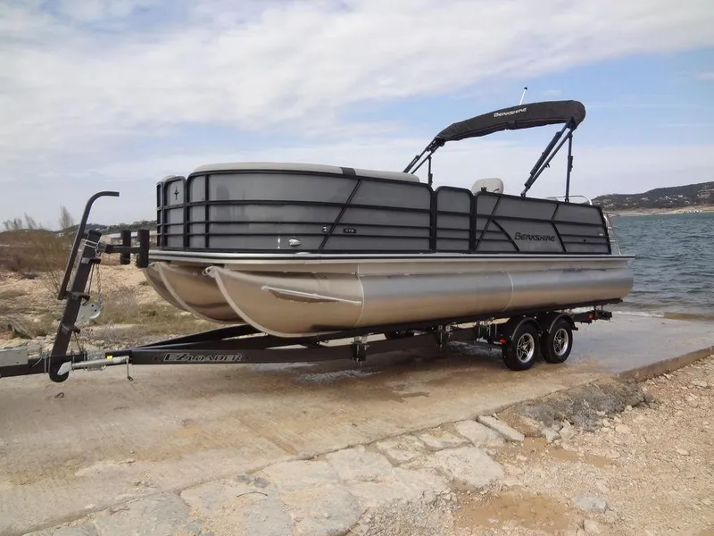Slide: The Image of 2023 Berkshire 24UL CTS 3.0 pontoon boat on trailer by a lake. - 34