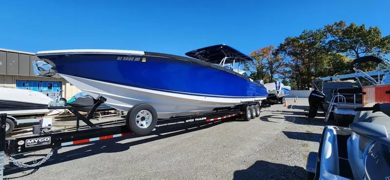 Slide: The Image of 2017 Nor-Tech 390 Center Console boat on trailer, vibrant blue hull, sunny day. - 2