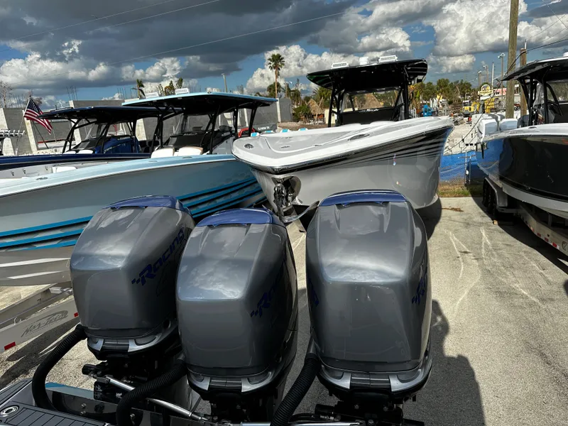 Slide: The Image of 2017 Nor-Tech 390 Center Console boats with triple outboard engines, parked under cloudy skies. - 21