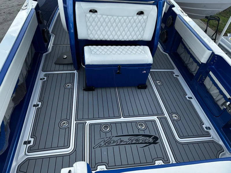 Slide: The Image of 2017 Nor-Tech 390 Center Console boat interior with blue and white seating and custom flooring. - 8