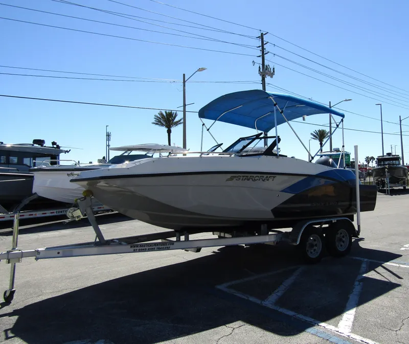 Slide: The Image of 2023 Starcraft SVX 190 OB boat on trailer with blue canopy in parking lot. - 6