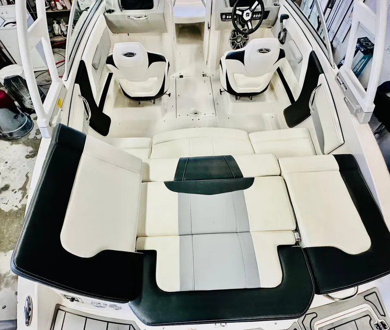 Slide: The Image of 2023 Chaparral 21 Surf boat interior with white and black seating in a garage setting. - 16
