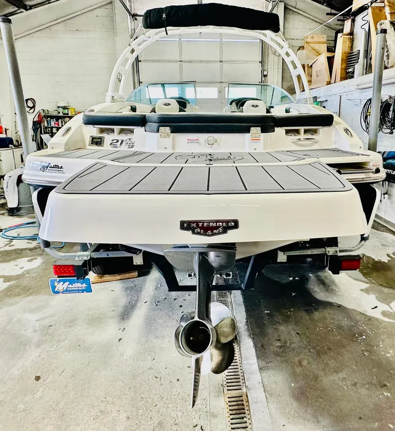 Slide: The Image of 2023 Chaparral 21 Surf boat in a garage, rear view with propeller visible. - 5