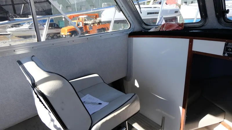 Slide: The Image of Interior of a 1999 Osprey 24 boat with a white seat and window view. - 11