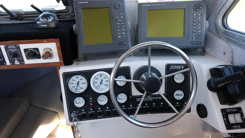 Slide: The Image of 1999 Osprey 24 boat dashboard with steering wheel, gauges, and navigation screens. - 3