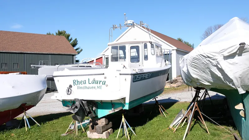 Slide: The Image of 1999 Osprey 24 boat named "Rhea Laura" on stands in a yard. - 4