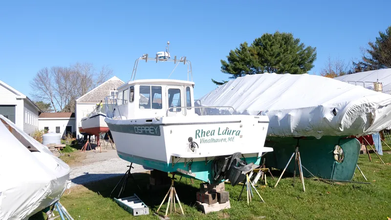 Slide: The Image of 1999 Osprey 24 boat "Rhea Laura" on land, surrounded by covered boats. - 5