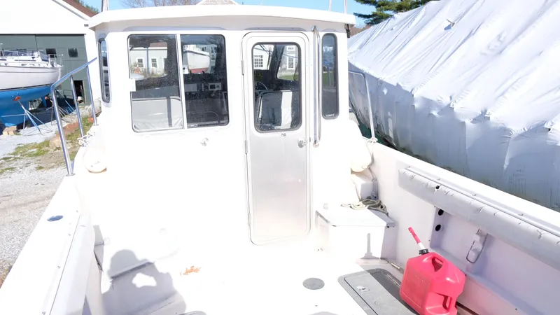 Slide: The Image of 1999 Osprey 24 boat with cabin, docked outdoors, red fuel container on deck. - 6