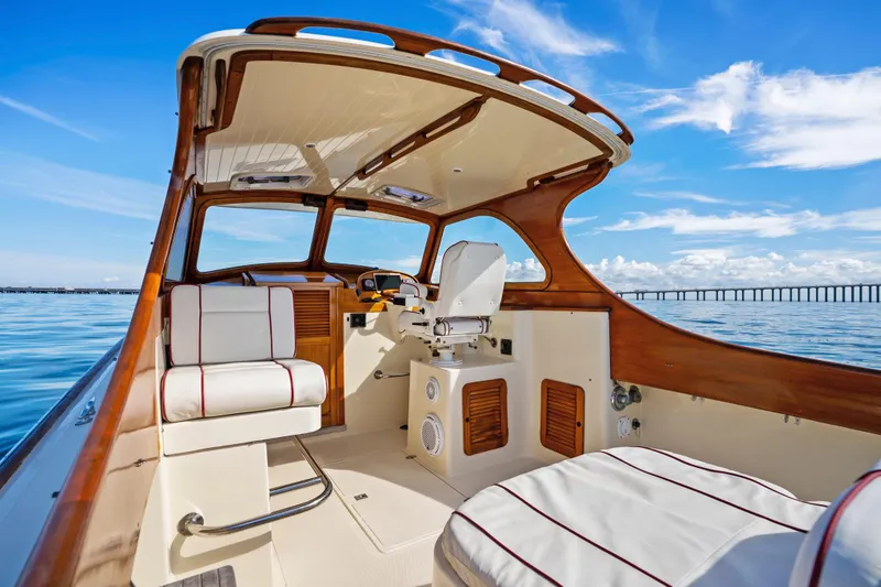 Slide: The Image of 1996 Hinckley 36 Picnic Boat Classic interior with elegant seating and steering, under a clear blue sky. - 12