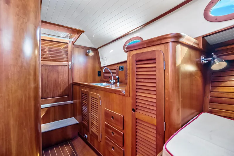Slide: The Image of Interior of 1996 Hinckley 36 Picnic Boat Classic with wooden cabinetry and compact sink area. - 19