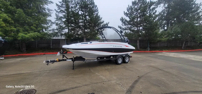 The Image of Tahoe 1950 boat 2023 model on trailer in parking lot with trees in background. - 0