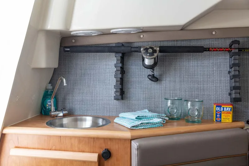 Slide: The Image of Compact kitchenette in 2023 Solara S-250 CW boat with sink, fishing rod, and Old Bay seasoning. - 25