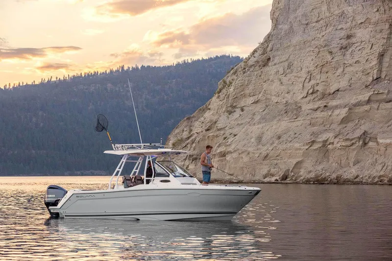 Slide: The Image of 2023 Solara S-250 CW boat on a serene lake near rocky cliffs at sunset. - 29