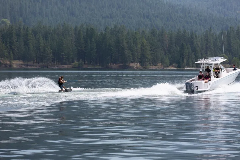 Slide: The Image of Person wakeboarding behind a 2023 Solara S-250 CW boat on a lake with forested hills. - 4