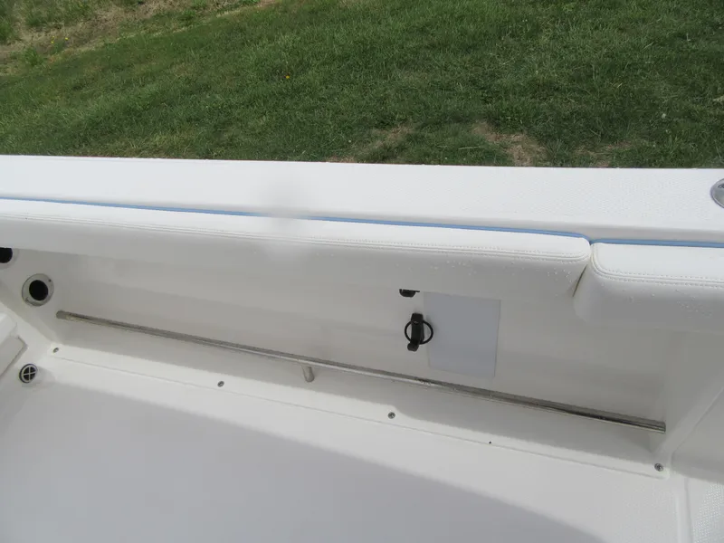 Slide: The Image of 2023 Robalo R222 Center Console boat interior detail with white seating and green grass background. - 15