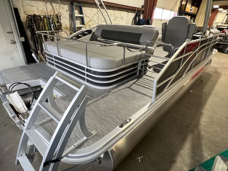 Slide: The Image of 2023 Bennington 22SXSB pontoon boat in a garage, featuring sleek design and spacious seating. - 15