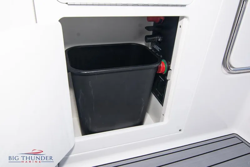 Slide: The Image of 2023 Monterey M6 boat storage compartment with black trash bin. - 26