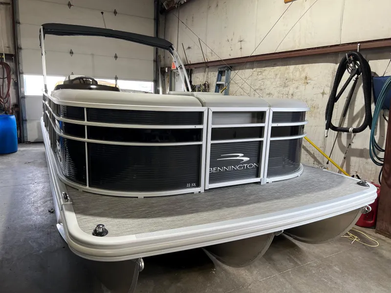 Slide: The Image of 2023 Bennington 22SXSB pontoon boat in a garage setting. - 1