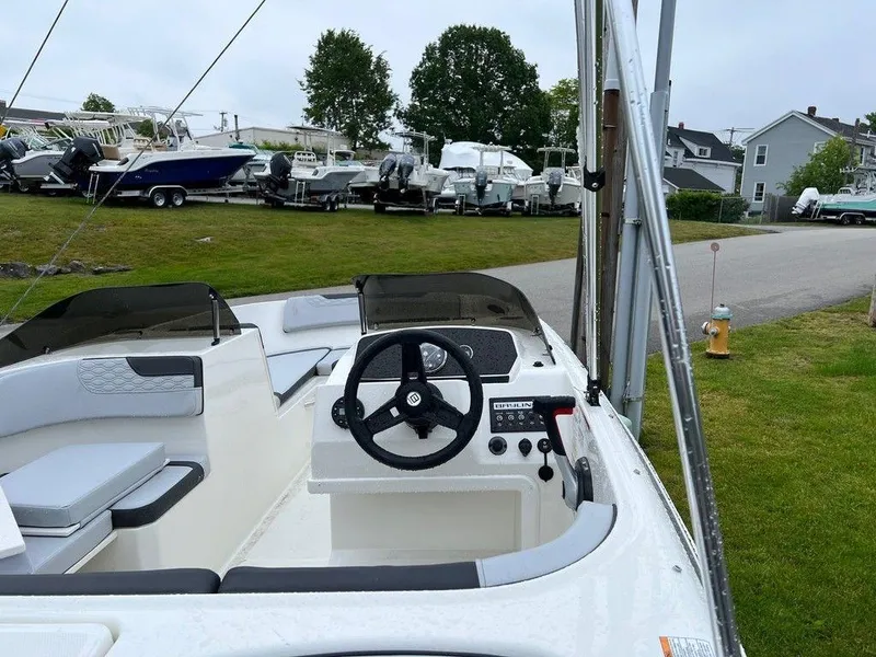 Slide: The Image of 2023 Bayliner Element M17 boat interior with steering wheel and seating, docked near other boats. - 4